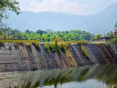 a dam on a river with mountains in the background at Siruvani Forest Farmstay By Shivalaya Stays in Coimbatore