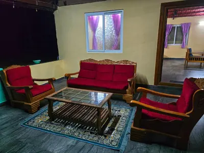 a living room with two chairs and a red couch at Siruvani Forest Farmstay By Shivalaya Stays in Coimbatore