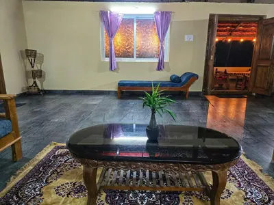 a living room with a table and a couch at Siruvani Forest Farmstay By Shivalaya Stays in Coimbatore