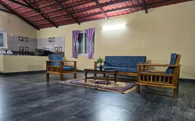 a living room with two chairs and a table at Siruvani Forest Farmstay By Shivalaya Stays in Coimbatore