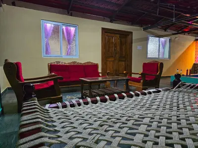a stage with chairs and a table in a room at Siruvani Forest Farmstay By Shivalaya Stays in Coimbatore