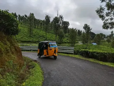 a small car driving down a road at blue Mount stay in Gūdalūr