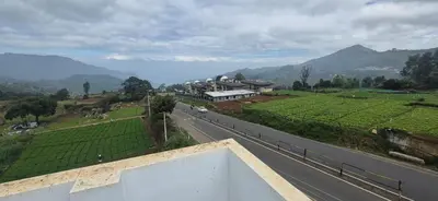 a house on the side of a road next to a mountain at IndivaStays - Sixface Park in Ooty