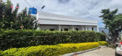 a white house with a hedge in front of it at IndivaStays - Sixface Park in Ooty