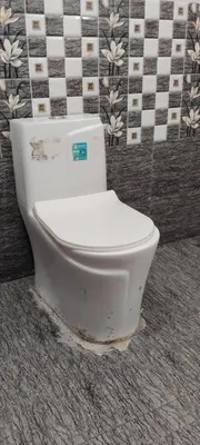 a white toilet in a bathroom with a tiled wall at Thendral Stay Marayoor in Marayoor