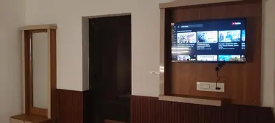 a flat screen tv in a room with a door at Thendral Stay Marayoor in Marayoor