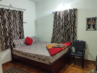 a small bed in a room with a chair at Arnold Home Stay Ooty in Ooty