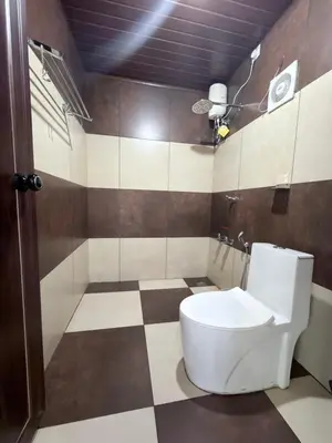 a bathroom with a toilet and a checkered floor at Aditi By Greenleaves Resort Vythiri in Vythiri