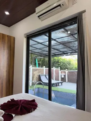 a bedroom with a bed and a view of a patio at Aditi By Greenleaves Resort Vythiri in Vythiri