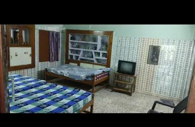 a room with two beds and a tv in it at Om Cottage in Palani