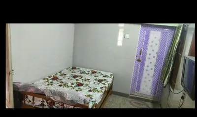 a small bedroom with a bed and a purple door at Om Cottage in Palani