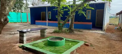 a building with a barrel and a table in a dirt yard at Lavi's Homestay in Hārohalli