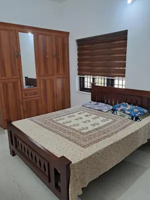 a bedroom with a large bed with a wooden frame at Vilasini Nivas in Irinjālakuda