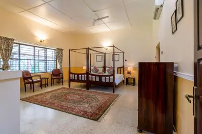 a bedroom with a bed and a living room at amã Stays & Trails - Woshully Bungalow, Coorg in Gonikoppal
