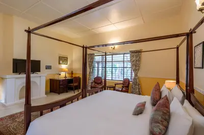 a bedroom with a canopy bed and a desk at amã Stays & Trails - Woshully Bungalow, Coorg in Gonikoppal