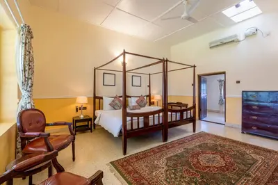 a bedroom with a four poster bed and a chair at amã Stays & Trails - Woshully Bungalow, Coorg in Gonikoppal