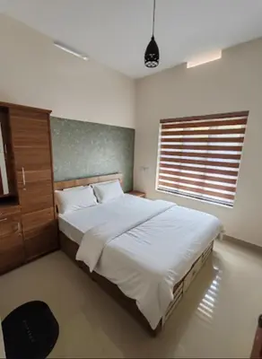 a bedroom with a large bed and a window at Elnido Holiday Home in Meppādi