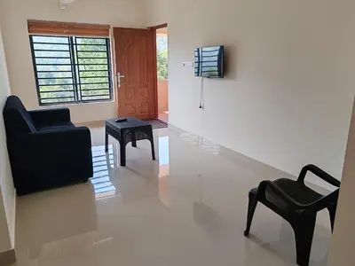 a living room with a black chair and a chair at Elnido Holiday Home in Meppādi