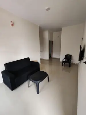 a living room with a black couch and a stool at Elnido Holiday Home in Meppādi