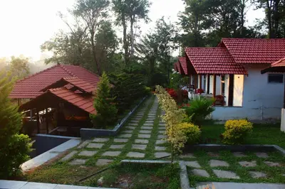 a house with a walkway in front of a yard at Aranya Cottage Coorg in Suntikoppa