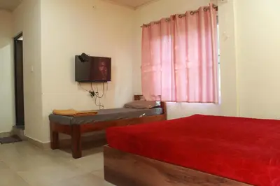 a bedroom with a bed and a tv and a window at Aranya Cottage Coorg in Suntikoppa