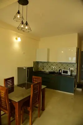a kitchen with a table and chairs and a microwave at Nirantara Luxury Service Apartment in Gonikoppal