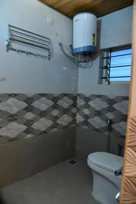 a bathroom with a toilet and a water tank at Nirantara Luxury Service Apartment in Gonikoppal