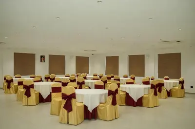 a banquet hall with tables and chairs with white and golditures at Dwaraka INN