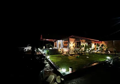 a house with lights in the yard at night at Sol Malai Retreat near MM Hills by Travent Mug