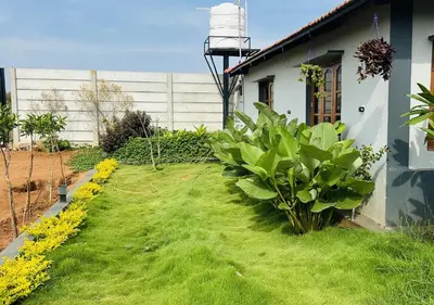 a yard with green grass and flowers next to a house at Sol Malai Retreat near MM Hills by Travent Mug