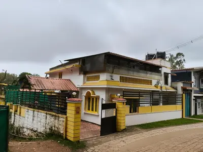 a yellow and white house with a building at White House Resort in Ooty