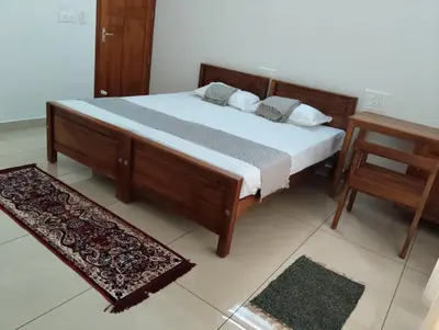a bedroom with a bed and two tables and a chair at Mellow Villa cochin airport in Angamali