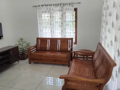 a living room with two wooden benches and a window at Mellow Villa cochin airport in Angamali