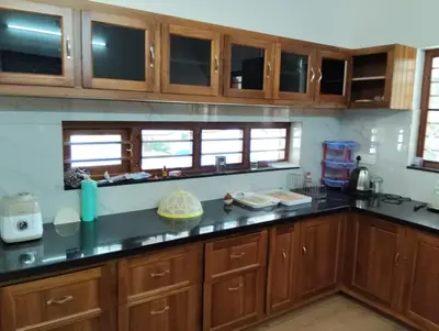 a kitchen with wooden cabinets and black counter tops at Mellow Villa cochin airport in Angamali