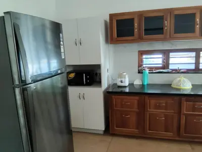 a kitchen with a stainless steel refrigerator and wooden cabinets at Mellow Villa cochin airport in Angamali
