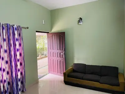 a living room with a couch and a pink door at Clement homes in Kalpetta