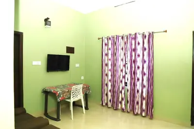 a room with a table and a curtain and a television at Clement homes in Kalpetta