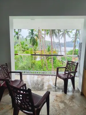 a room with two chairs and a large window at Riverbend Retreat in Kozhikode