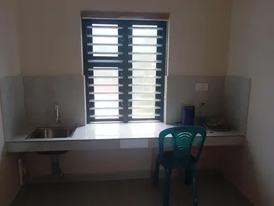 a kitchen with a sink and a window with a chair at PURAYIL Rooms in Kozhikode