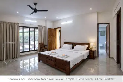 a bedroom with a large bed with a ceiling fan at Luxury Garden Villa, Free Breakfast in Guruvayoor in Manattala