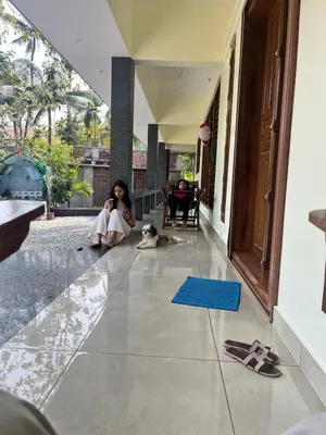 a woman sitting on the floor of a house with a dog at Luxury Garden Villa, Free Breakfast in Guruvayoor in Manattala