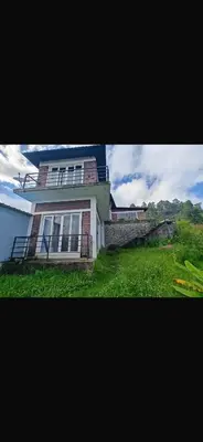 a house with a grass yard in front of it at Artists getaway in Kodaikānāl