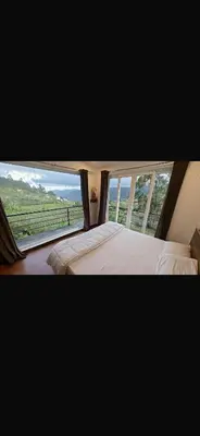 a bedroom with two beds and a large window at Artists getaway in Kodaikānāl