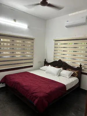 a bedroom with a bed with red sheets and white pillows at Entire 4BHK House with Full Kitchen near malayattoor in Kodanad