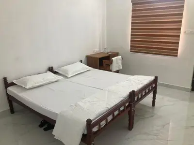 a bedroom with a bed and a table and a window at vhost in Alwaye