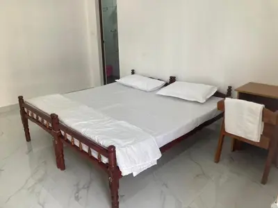 a bed with two pillows and a table in a room at vhost in Alwaye