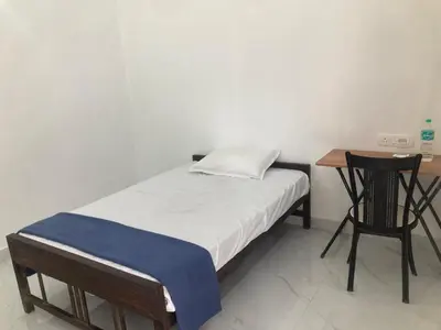 a small bedroom with a bed and a desk at vhost in Alwaye