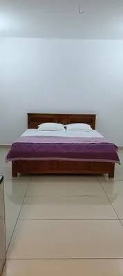 a bed in a white room with a purple mattress at Metta Heaven in Kodenchery