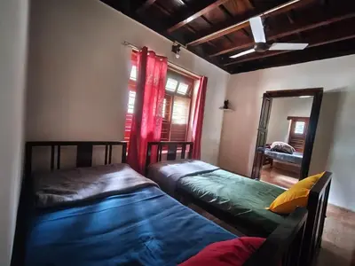two beds in a room with a mirror and red curtains at Heritage Mudhouse Homestay in Virajpet