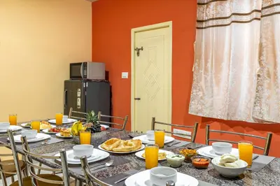 a dining room with a table with food and orange walls at Orchid Villa Kotagiri in Kodanād